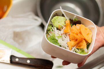 明日のお弁当を前日の晩に準備中。生野菜と柿のサラダを弁当箱に詰めます