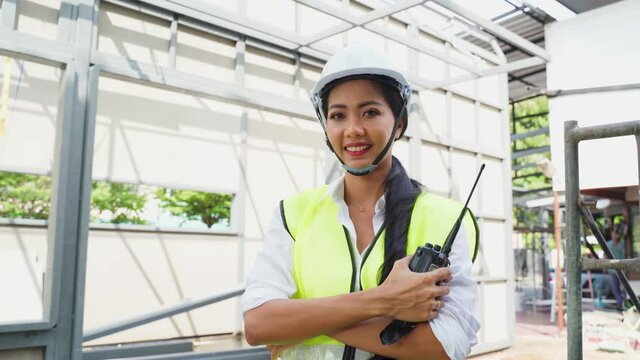 Portrait of Asian female engineer standing and holding walkie-talkie.