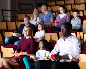 international parents with children sitting at movie in cinema
