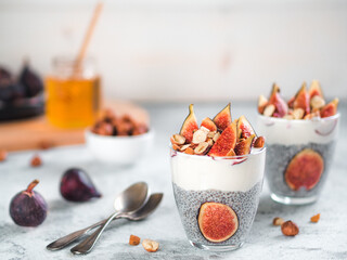 Healthy chia pudding with yogurt, figs and nuts in glass. Ideas and recipes for healthy breakfast, snack or dessert. Two glass with chia seeds pudding with copy space for text.