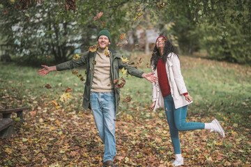 Fototapeta premium Young couple enjoying playing with beautiful autumn leaves