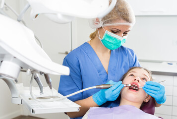 Female dentist with girl patient during oral checkup in modern dentistry.