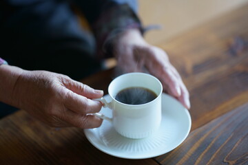 コーヒーを飲む高齢女性の手元