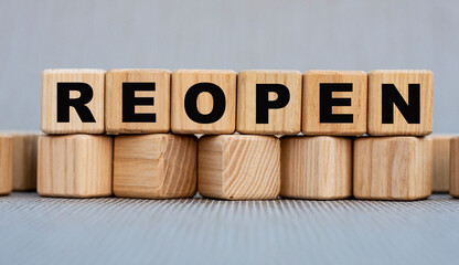 REOPEN - word on wooden cubes on a beautiful gray background