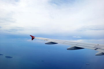 a small island and ship at the sea viewed from airplane window with airplane wings