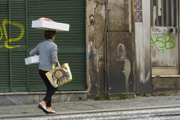 Obraz na płótnie Canvas woman carrying a crate on her head in the old town of Porto, Portugal