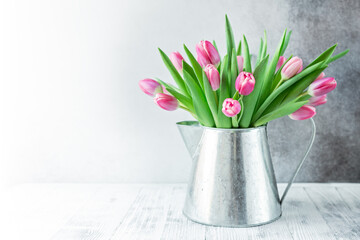Spring floral background. Pink tulip flowers bouquet on shelf in front of stone wall. Copy space