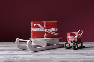 Big and small red gift boxes on Santa sleight over dark pink background. Christmas and New Year holiday greeting