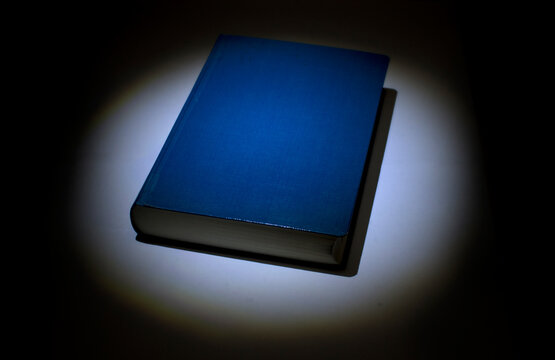 Blue Book On The Table. Direct Light On The Book. Book In The Dark. 