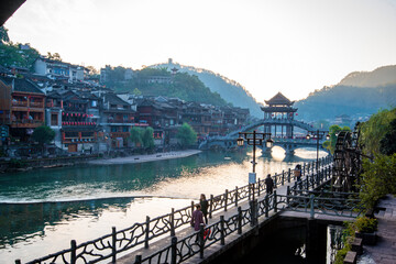 the river, the boat, stone bridge and the old houses at ancient phoenix town in the morning at...