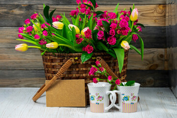 Fototapeta na wymiar beautiful bouquet of flowers red roses and tulips in a wooden basket 