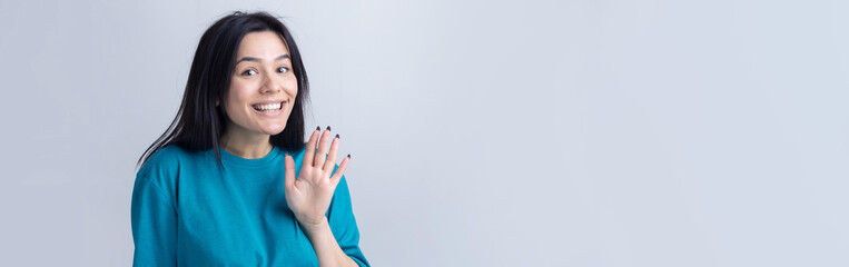 Smiling woman  raised her hand palm up and forward like waving.