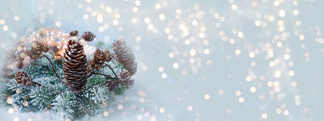 Christmas winter background - banner with pastel blue soft frame with pine cones and bokeh lights