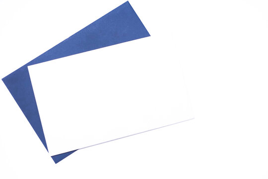 Blank white card on blue envelope. Minimalist composition on white background. Top view, empty space for text.
