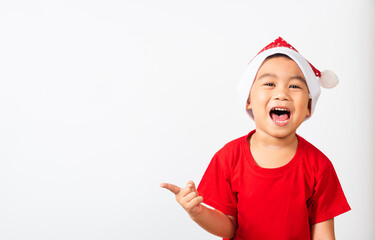 Asian little cute child boy smile and excited, Kids dressed in red Santa Claus hat point finger to side away the concept of holiday Christmas Xmas day or Happy new year, isolated on white background