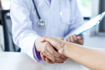 The doctor shook hands with an Asian woman patient after the examination was completed.