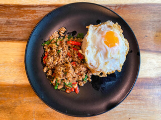 Rice topped with stir-fried pork and basil with a fried egg on the table