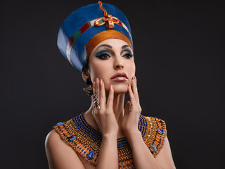 closeup studio portrait of a beautiful woman with brown eyes and evening make-up in the image of Queen Nefertiti, crown, necklace - obrazy, fototapety, plakaty