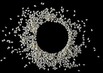 Sesame seeds with round blank frame and border isolated on black background, top view