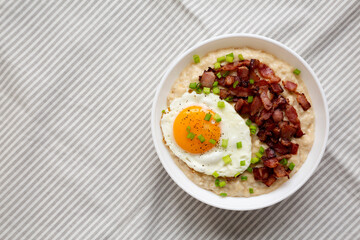 Homemade Cheesy Bacon Savory Oatmeal Bowl on cloth, view from above. Top view, overhead, flat lay. Copy space.