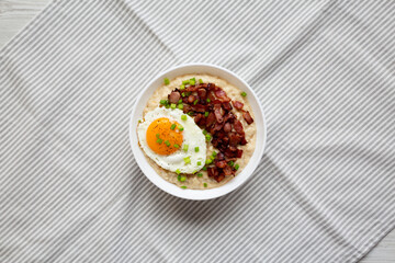 Homemade Cheesy Bacon Savory Oatmeal Bowl on cloth, view from above. Top view, overhead, flat lay.