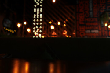 Blurred night cafe Background. Lamp and lettering on background. Table and reflection on foreground. Copy space.