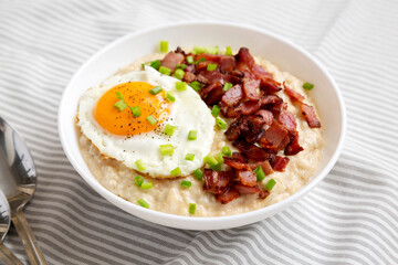 Homemade Cheesy Bacon Savory Oatmeal Bowl on cloth, low angle view.
