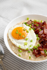 Homemade Cheesy Bacon Savory Oatmeal Bowl on cloth, low angle view.