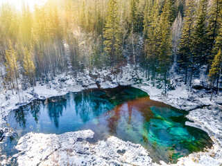 Beautiful amazing landscape of mountain ice-free lake surrounded by a winter forest. Geyser lake is a famous attraction of the Altai mountains. Siberia, Russia. top view, aerial view,