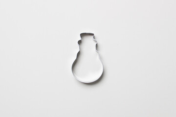 cookie cutter in form of snowman on white colored paper background. isolated. close up. mock up