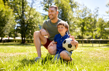 Naklejka premium family, fatherhood and people concept - happy father and little son with soccer ball at summer park