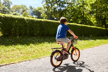 Fototapeta premium childhood, leisure and people - little boy riding bicycle at summer park