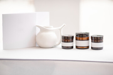 Composition of a glass bottles with empty stickers to copy paste and teapot on the white background