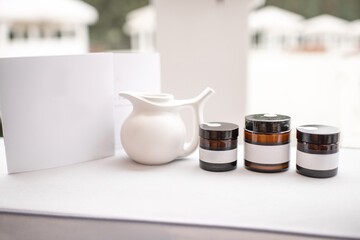 Composition of a glass bottles with empty stickers to copy paste and teapot on the white background