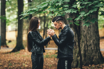 Young couple in forest nature park in late autumn. The man warms girl's hands.