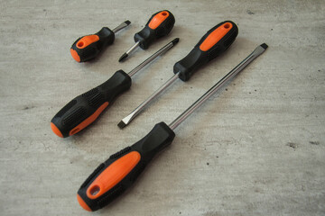 Construction and repair tools. Set on a wooden background. Metal screwdrivers and pliers with black and orange handles. Equipment for electrician, plumber and installer