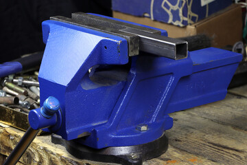 Blue vise on a wooden table. Bench tools. Vice