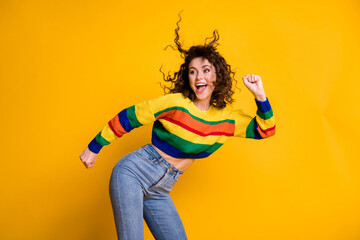 Photo of shiny funny woman dressed casual colorful sweatshirt dancing looking empty space hands arms fists isolated yellow color background