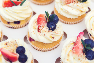 Holidays cupcakes with strawberry and blueberry, close up. Cupcakes packaging, delivery box. Gift box with sweets. Sweet shop. Present box full of fruit cupcakes.