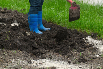 Female Farmer Mixing the Soil and Fertilizers to prepare for Planting in the Garden.