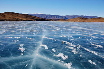Frozen Lake Baikal in winter. Small Sea Strait in sunny frosty day, transparent smooth ice with cracks.