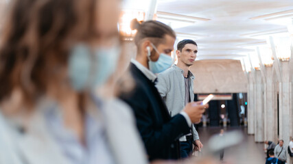 people in protective masks standing at the subway station .