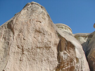 The man feels like an insect surrounded by giant impregnable white rocks in the midday sun.