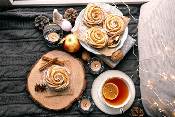 A cup of hot tea with lemon in an early winter morning by the window. Knitted wool warm blanket, hot homemade apple cakes with cinnamon and star anise . Decor. Home winter holiday concept.