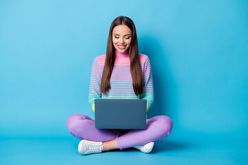 Portrait of lovely focused cheery girl sitting lotus position crossed legs using laptop isolated on...