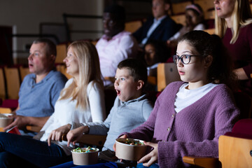 Portrait of emotional teen girl looking scared or shocked while watching movie in cinema
