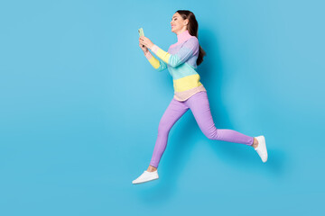 Fototapeta na wymiar Full length body size view of nice focused cheery girl jumping using cell app 5g walking chatting isolated on bright blue color background
