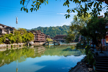 the river, the boat, stone bridge and the old houses at ancient phoenix town in the morning at...