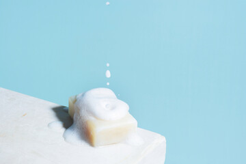 Piece of white soap and falling foam, concept of antibacterial protection