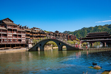 the river, the boat, stone bridge and the old houses at ancient phoenix town in the morning at...